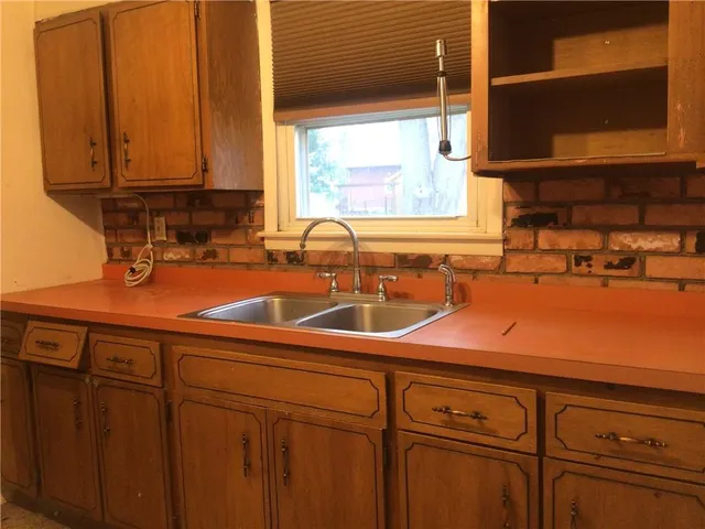 a kitchen with stainless steel appliances a sink cabinets and a window