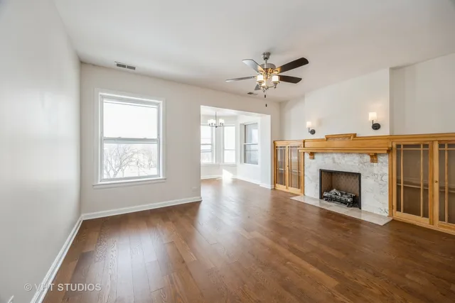a view of an empty room with wooden floor fireplace and a window