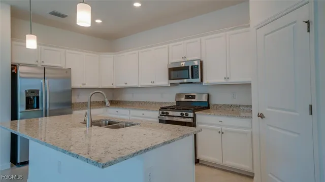 a kitchen with stainless steel appliances granite countertop a sink a stove and a refrigerator with wooden floor