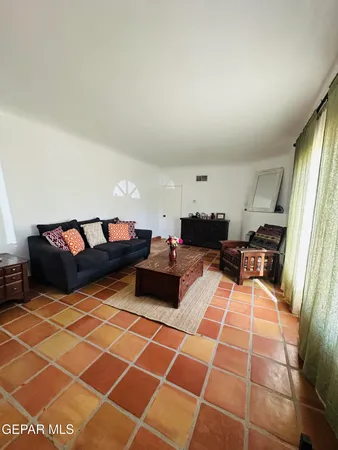 a living room with a black white checkered floor with a gaming machine and chairs