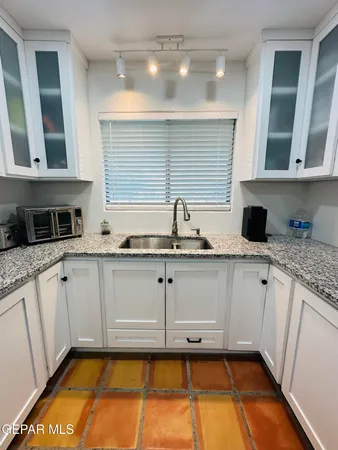 a kitchen with granite countertop a sink and cabinets