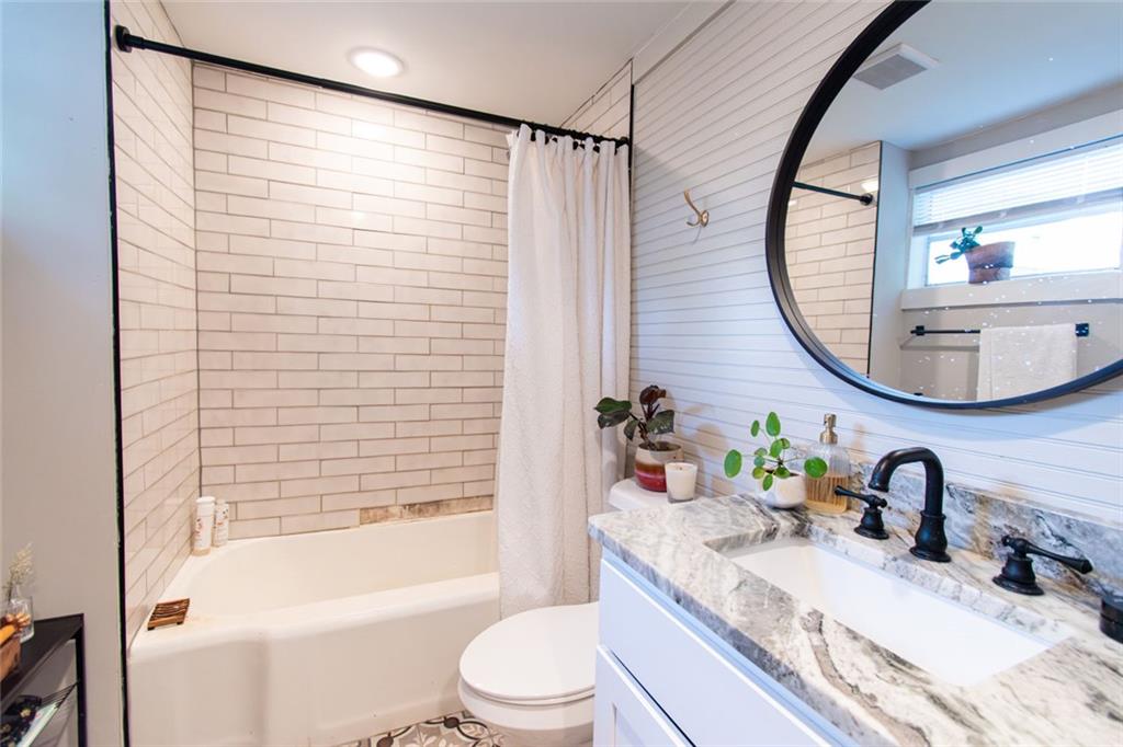 702 Radford Street Monroe, GA 30655 - Photo 20 of 49 a bathroom with a granite countertop sink toilet a mirror and bathtub