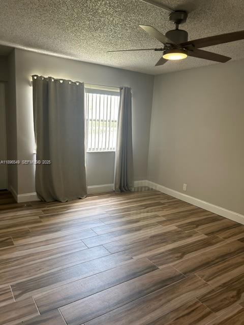 303 Racquet Club Road, Unit 106 Weston, FL 33326 - Photo 13 of 23 an empty room with wooden floor fan and windows