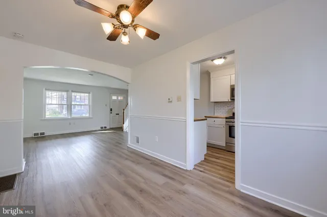 a view of empty room with wooden floor and ceiling fan