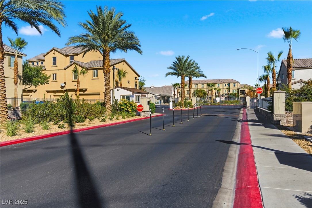 4648 Woolcomber Street Las Vegas, NV 89115 - Photo 37 of 41 View of asphalt road featuring traffic signs, a residential view, curbs, a gate, and sidewalks