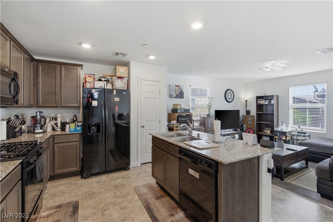 4648 Woolcomber Street Las Vegas, NV 89115 - Photo 39 of 41 Kitchen with open floor plan, dark brown cabinets, black appliances, light stone countertops, and recessed lighting