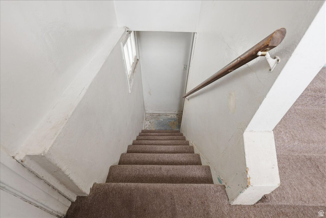 348 East 200 North Logan, UT 84321 - Photo 29 of 41 Stairwell featuring carpeted steps, a wood handrail, and a window providing natural light