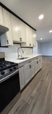 a kitchen with granite countertop stainless steel appliances a sink stove and cabinets