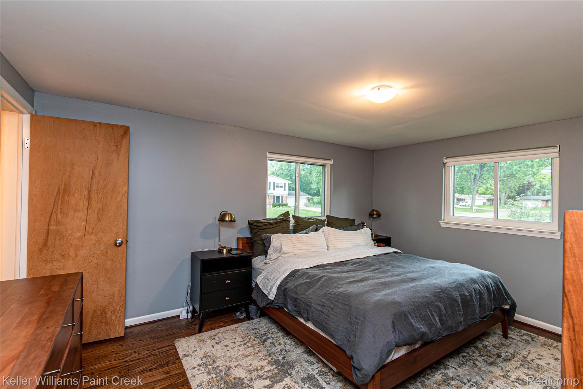 7093 Stonebrook Road West Bloomfield, MI 48322 - Photo 35 of 64 Spacious room featuring two windows with white trim, wood-finish flooring, and a flush-mount ceiling light fixture