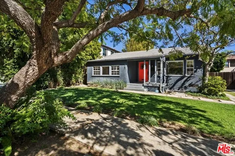 a front view of a house with a yard and palm trees
