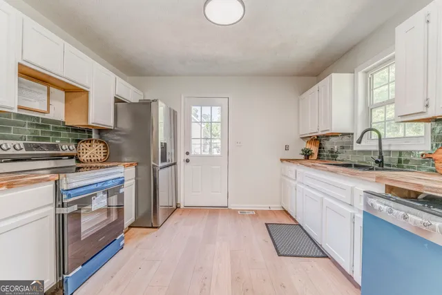 a kitchen with granite countertop a refrigerator oven a sink dishwasher and white cabinets with wooden floor