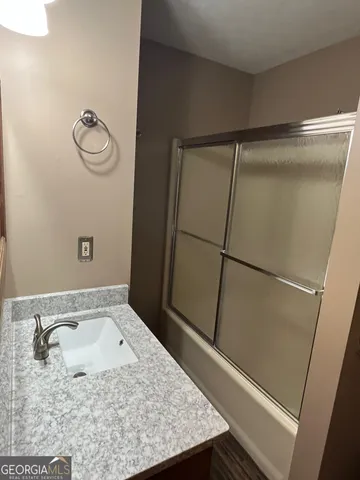 a bathroom with a granite countertop shower and a sink