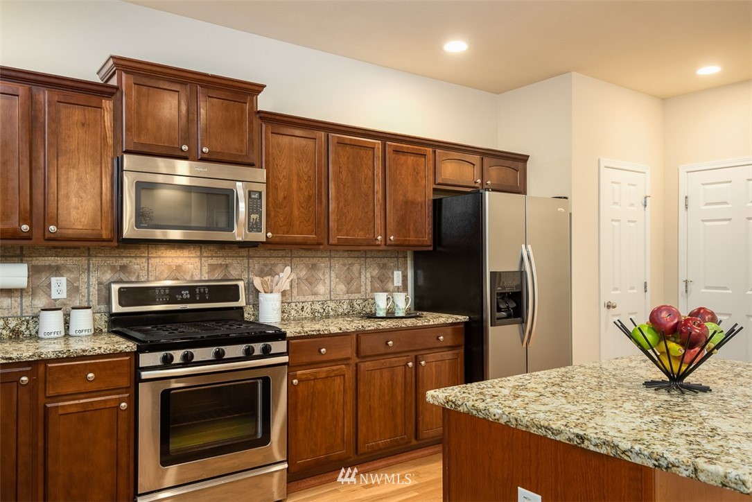 2719 232nd Street Southeast Bothell, WA 98021 - Photo 12 of 24 a kitchen with stainless steel appliances granite countertop a stove microwave refrigerator and sink