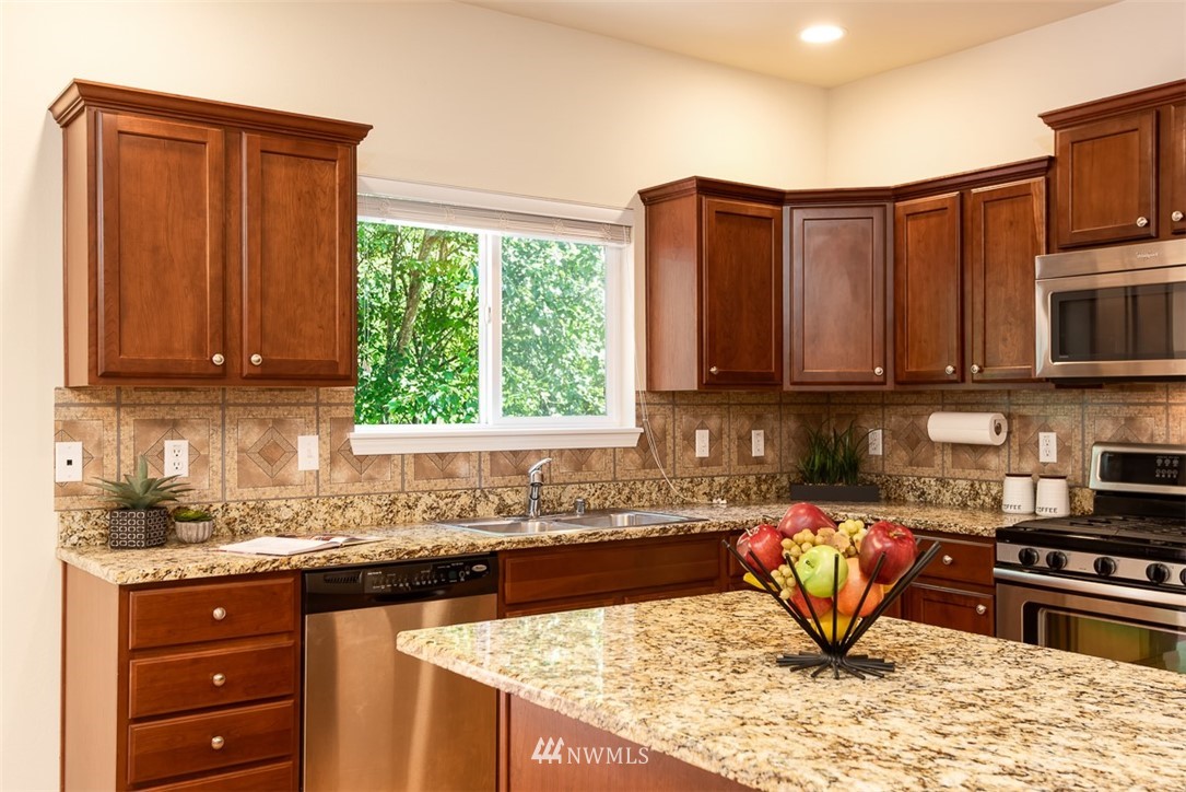 2719 232nd Street Southeast Bothell, WA 98021 - Photo 9 of 24 a kitchen with stainless steel appliances granite countertop a stove a sink dishwasher and cabinets with wooden floor