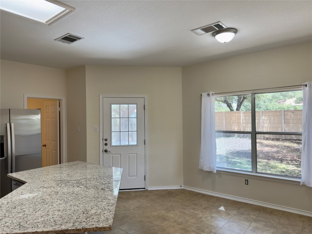 1206 Devil Ridge Cedar Park, TX 78613 - Photo 9 of 38 Kitchen featuring healthy amount of natural light, stainless steel refrigerator with ice dispenser, and light stone counters