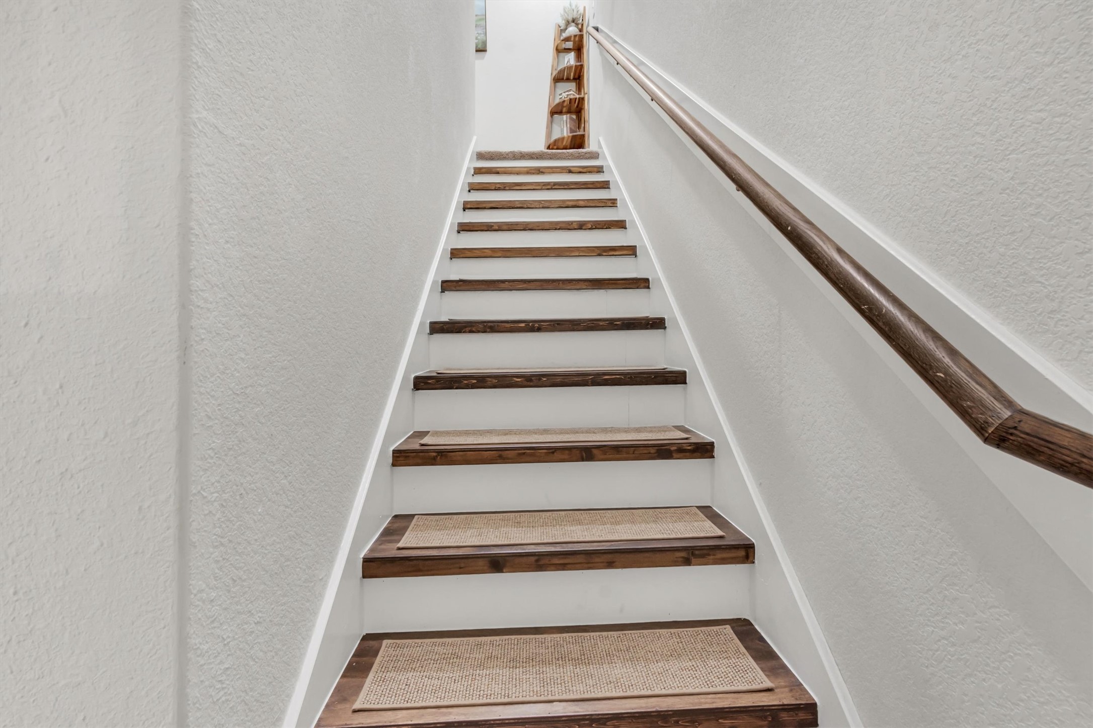 100 Wincliff Cove, Unit 13D Jarrell, TX 76537 - Photo 8 of 21 Hardwood style flooring continues up the steps and handrail provide a rustic accent to this bright stairwell.