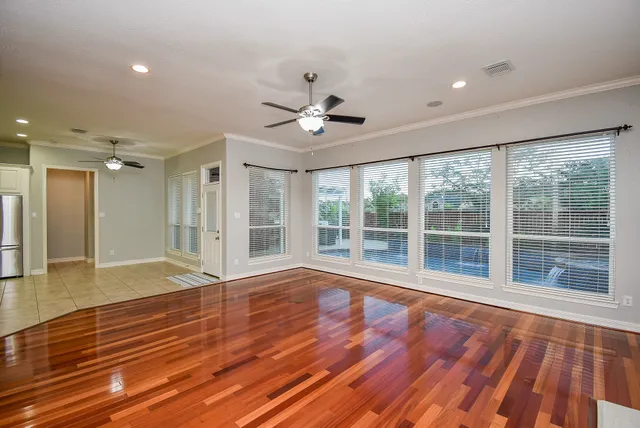 a view of empty room with wooden floor and fan
