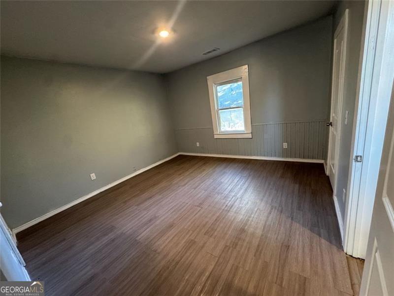 339 Main Street Griffin, GA 30223 - Photo 3 of 4 an empty room with wooden floor and windows
