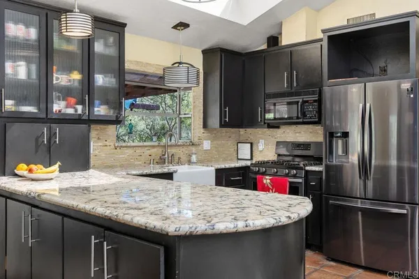 a kitchen with stainless steel appliances granite countertop a sink and a refrigerator