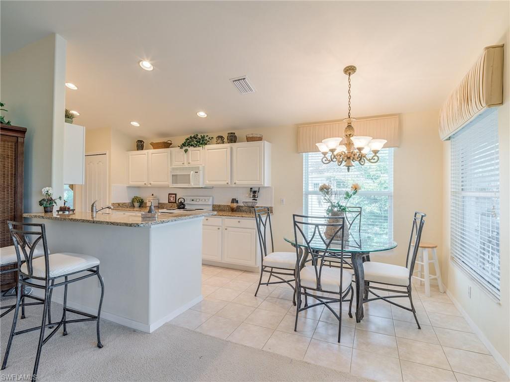9830 Spring Run Boulevard, Unit 3408 Estero, FL 34135 - Photo 11 of 24 a kitchen with a dining table chairs and white cabinets