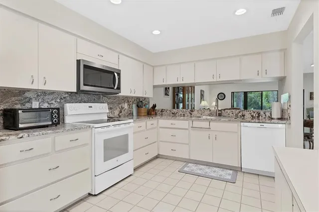 a kitchen with white cabinets appliances and sink