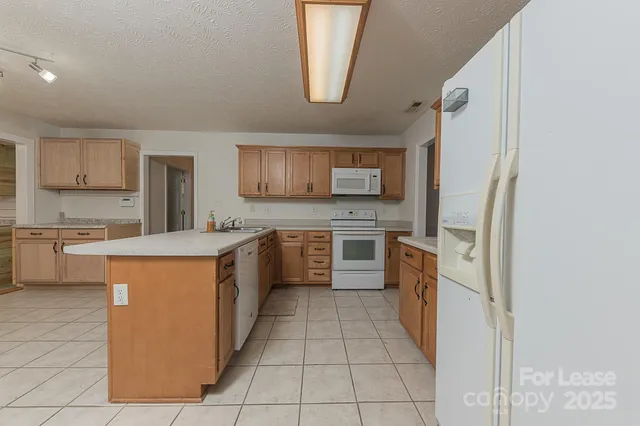a large kitchen with stainless steel appliances granite countertop a stove a sink dishwasher and a refrigerator