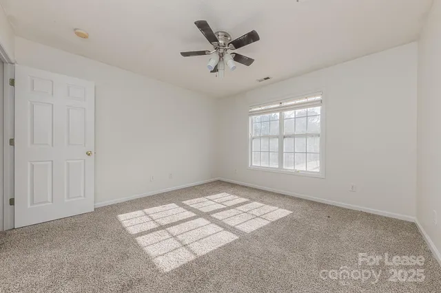 an empty room with windows and ceiling fan