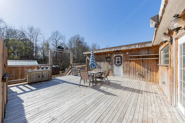 a view of a roof deck with table and chairs a barbeque with wooden floor and fence