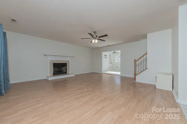 a view of an empty room with a fireplace and a ceiling fan