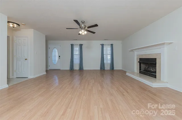 a view of empty room with a fireplace and wooden floor