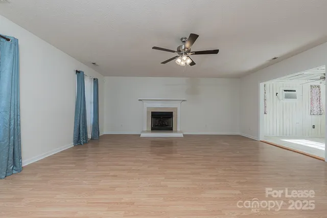 a view of an empty room with a fireplace and a window