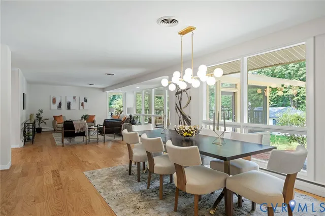 a view of a dining room and livingroom with furniture wooden floor a chandelier