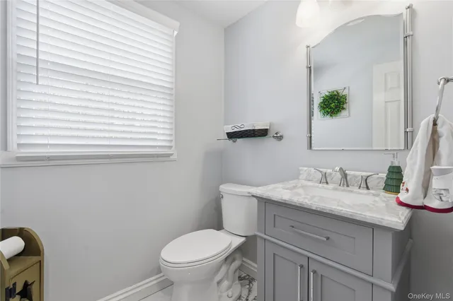 a bathroom with a granite countertop toilet sink and mirror