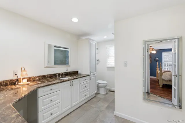 a spacious bathroom with a granite countertop sink a toilet and a mirror
