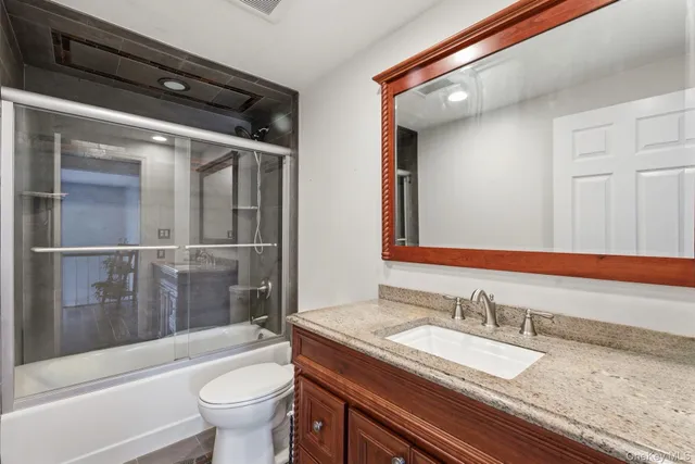 a bathroom with a granite countertop sink toilet and shower