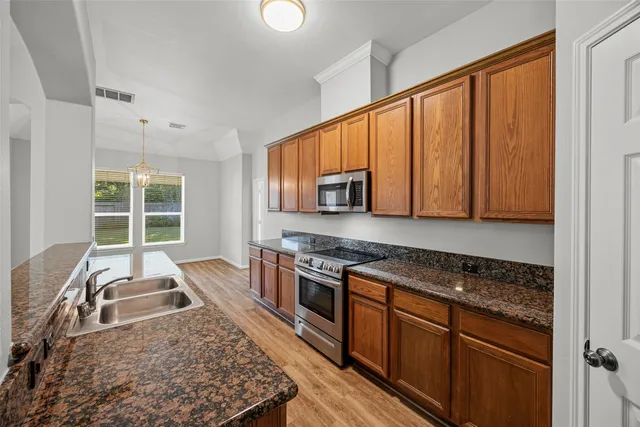 a kitchen with stainless steel appliances granite countertop a stove a sink and a microwave