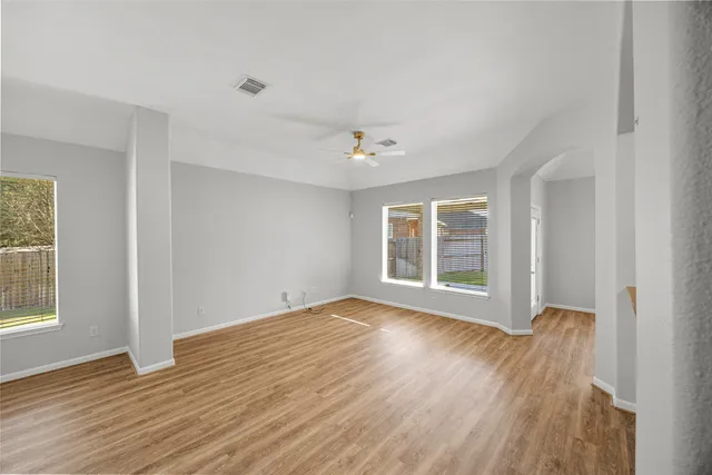 a view of an empty room with wooden floor and a window