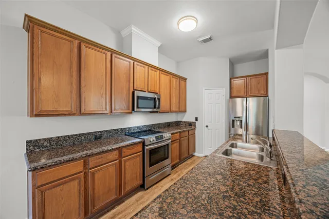 a kitchen with stainless steel appliances granite countertop a stove a sink and a refrigerator