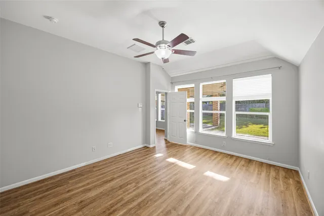 a view of an empty room with a window and wooden floor