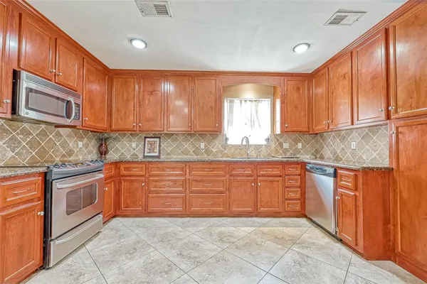 a large kitchen with granite countertop a stove sink and cabinets