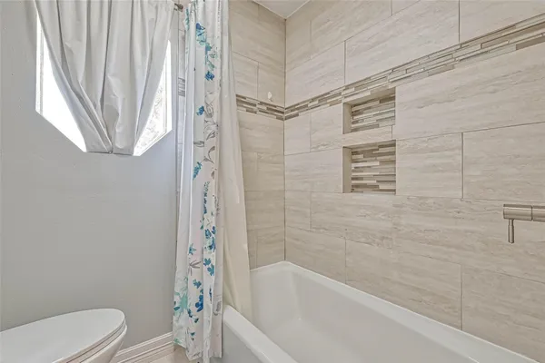 a bathroom with a shower a toilet and a bathtub