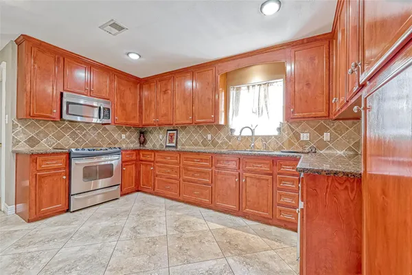 a kitchen with stainless steel appliances granite countertop a stove sink and cabinets