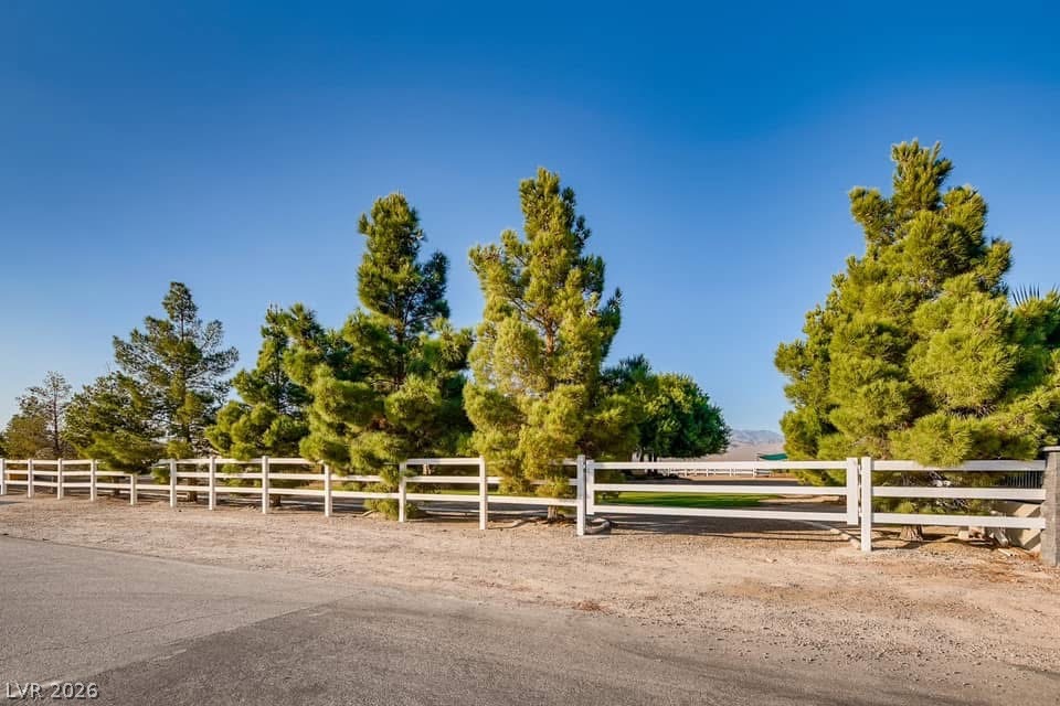 6460 Racel Street Las Vegas, NV 89131 - Photo 14 of 59 Stately perimeter fencing and mature evergreen trees frame the entrance of this expansive property.