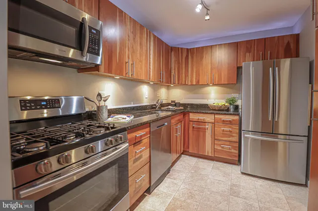 a kitchen with granite countertop a stove top oven microwave and cabinets