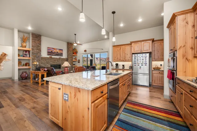 a kitchen with stainless steel appliances kitchen island granite countertop a refrigerator a stove and a sink with cabinets