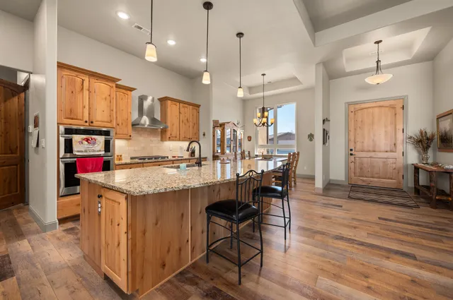 a kitchen with stainless steel appliances kitchen island granite countertop a table chairs and a refrigerator