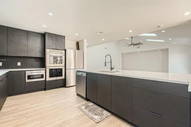 a kitchen with stainless steel appliances kitchen island granite countertop a sink a stove and cabinets