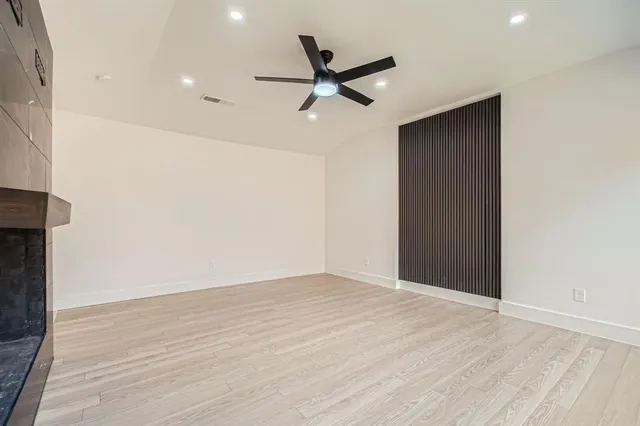an empty room with wooden floor and a ceiling fan