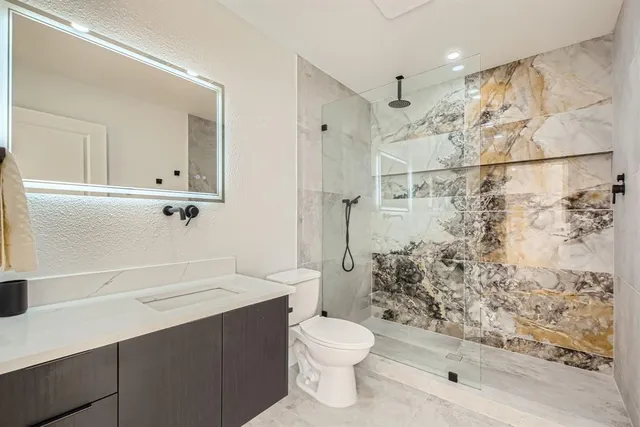 a bathroom with a sink a toilet and shower