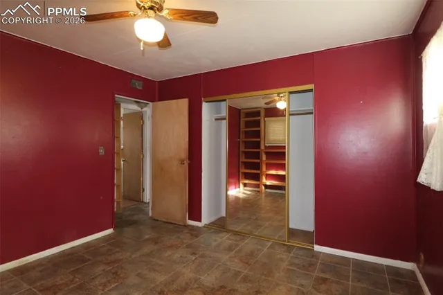 an empty room with closet and a ceiling fan